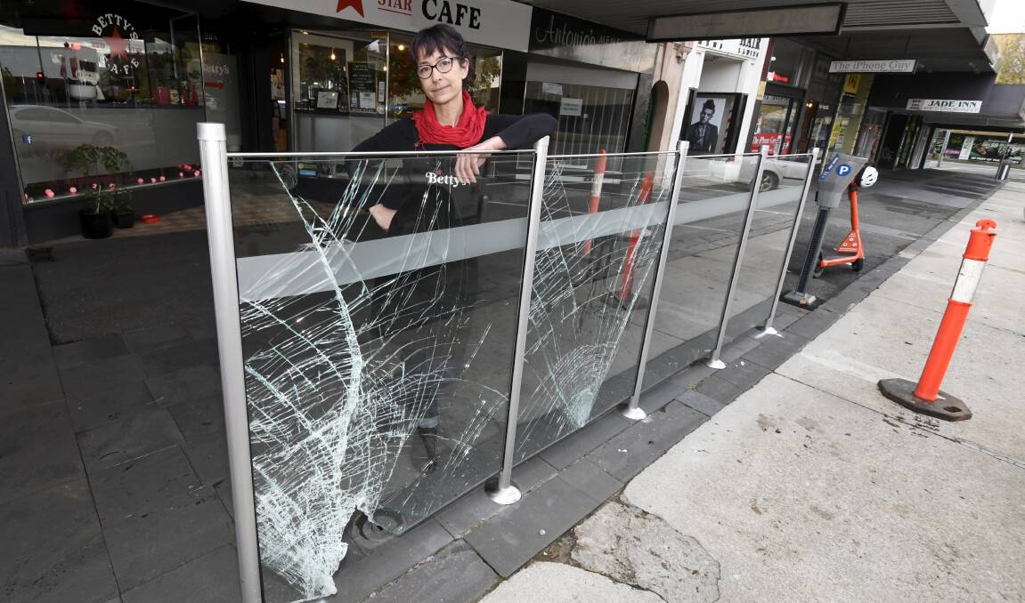 Betty's Red Star Cafe owner Pia Sims inspects the glass damaged by an e-scooter. Picture: Lachlan Bence.