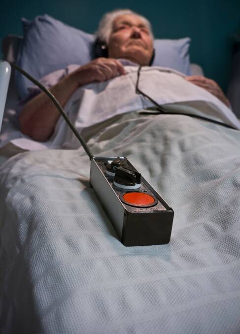 An elderly lady in hospital care bed at night with an emergency call button lying to her side. File photo.