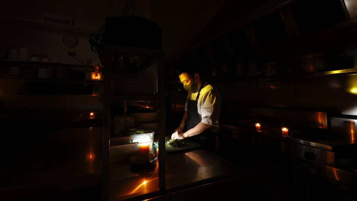 THE COVER OF DARKNESS: Saigon Allee head chef Dino Na prepares food under candlelight. Picture: Luke Hemer