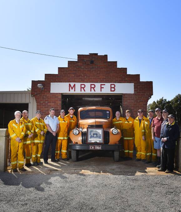 LIFETIME OF MEMORIES: Miners Rest CFA volunteers past and present stand next to the township's first fire truck. They will come together to celebrate the brigade's 75th anniversary next Sunday afternoon. Picture: Luka Kauzlaric  