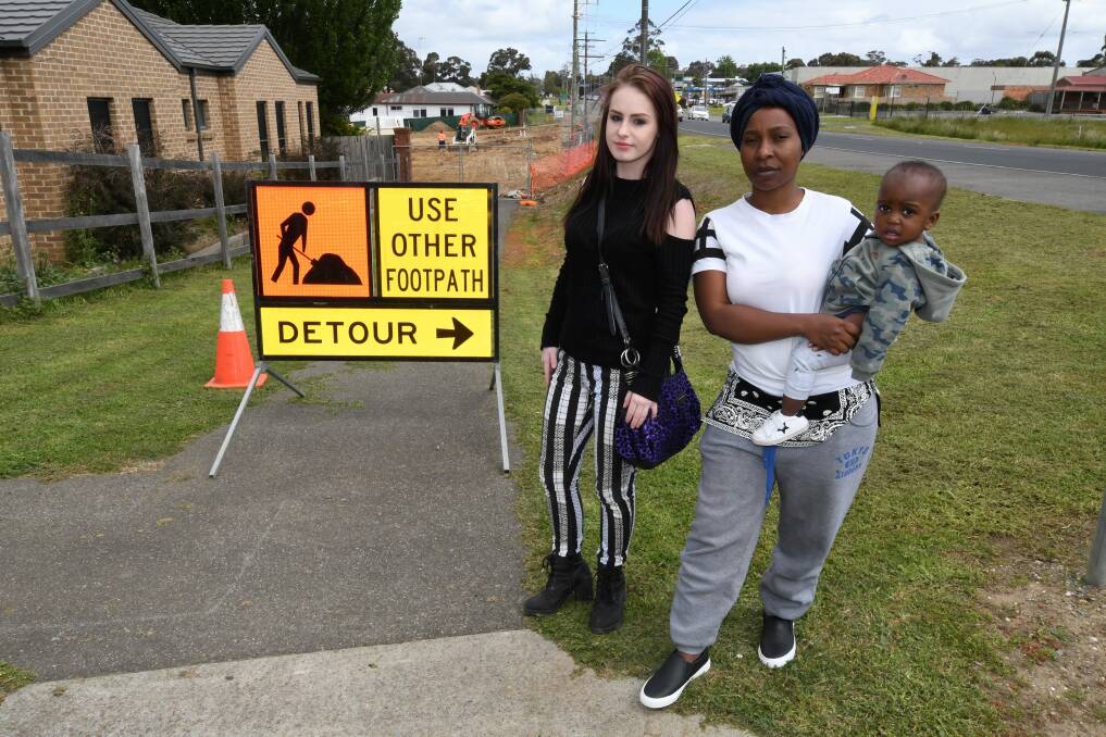 UNHAPPY: Mount Clear residents Shelby Briggs and Renatha Nshimirimana, with one-year-old Augustice Nvrekezi at the closed section of footpath. Picture: Lachlan Bence