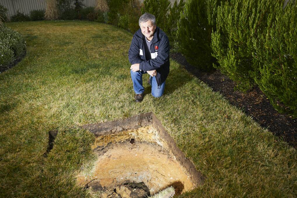 Andrew Rolt examines the sinkhole that opened up in his backyard. Picture: Luka Kauzlaric