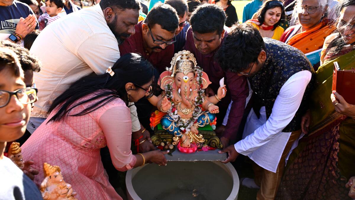 Raveen Chilukuri, Prem Anand and Gobi Anand (middle three) perform the Ganesha Visarjan by submerging a statue of Ganesh in water outside the hall. Picture by Adam Trafford. 