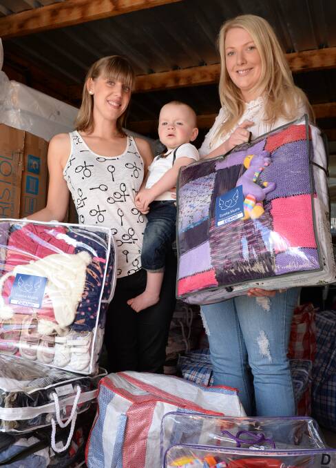 Helpers: Erin Malone and Shae Eva with Tyler Campbell with the packs they send out to vulnerable families as part of the Eureka Mums group. PICTURE: Kate Healy. 