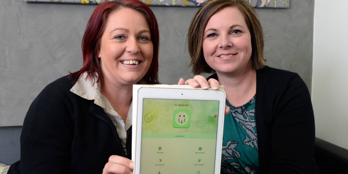 HELPING HAND: Psychologist Amanda Commons-Treloar, right, shows her MyPsyDiary app to Survivors of Suicide founder Kristy Steenhuis, who has organised the Stomp Out the Stigma football match. Picture: Kate Healy