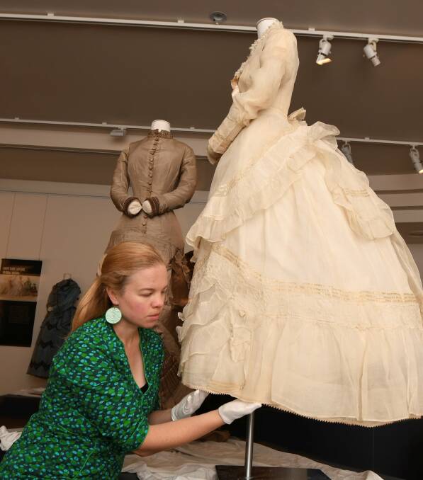 RARE: Fashion exhibition curator Snjez Cosic adjusts an 1874 wedding dress worn by Fanny Perrin, the daughter of business owner, Eliza Perrin. Picture: Lachlan Bence