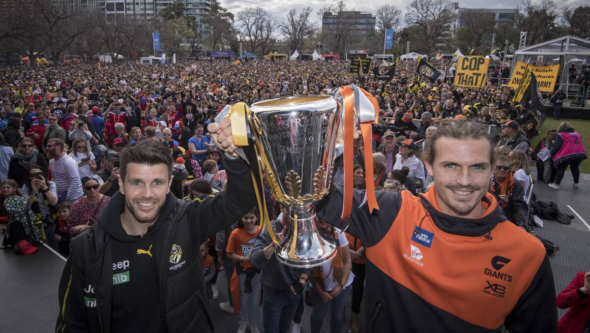 READY: Richmond captain Trent Cotchin and GWS captain Phil Davis get their hands on the silverware ahead at the AFL grand final parade. Picture: The Age