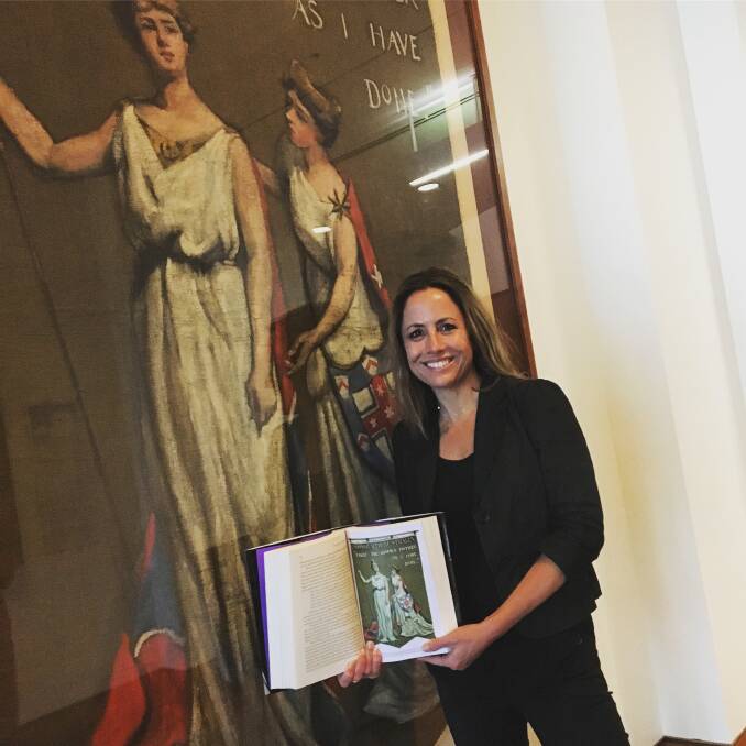 Historian Clare Wright stands with her book by Dora Meeson Coates' controversial Australian banner carried in the British feminist activist marches of 1908 and 1911. 