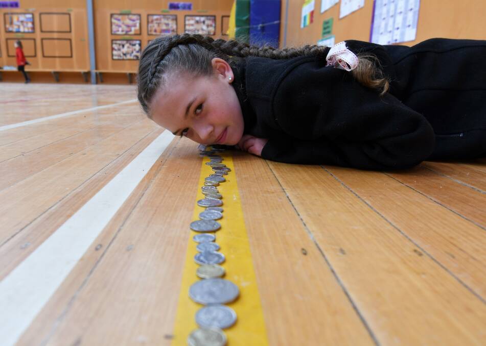 LINE-UP: Buninyong school captain Matilda sizes up some of the spare change from pupils to create change for children in Malawi. Picture: Lachlan Bence
