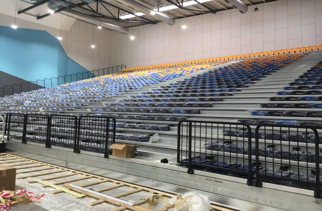 Retractable seating takes shape along one side of the showcourt arena.
