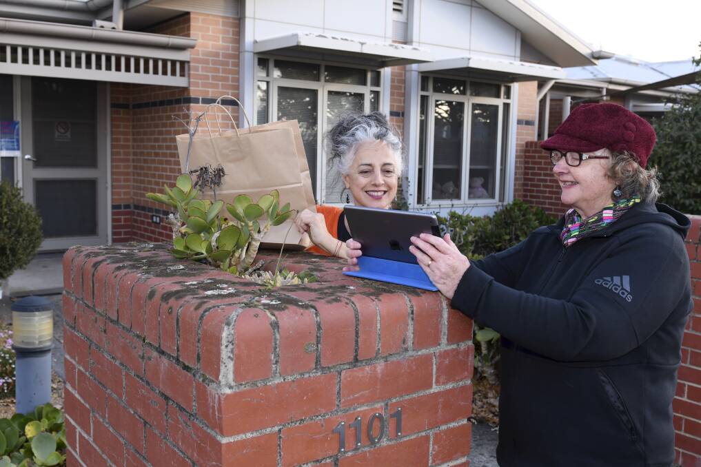 EXCHANGE: Bill Crawford Lodge leisure and lifestyle coordinator Christine McGoldrick and Ballarat Health Services volunteer Dale work to keep connections with residents amid lockdowns. Picture: Lachlan Bence