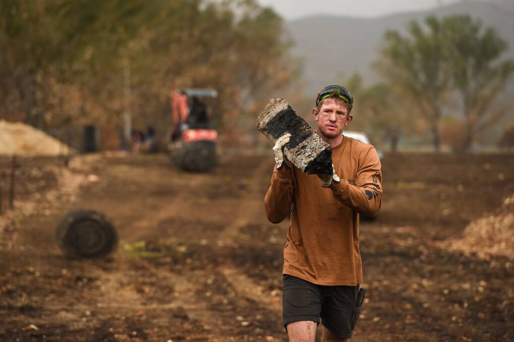 GIVING BACK: Hawthorn's Sam Frost helps rebuild fences in bush fire affected regions in the Upper Murray in January. Picture: Mark Jesser