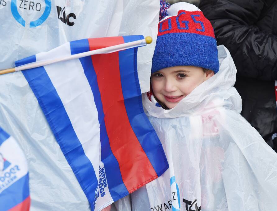 SPIRIT: Four-year-old Maeve rugs up and stays dry under a poncho and makes the most of experiencing football in her hometown when so many others spoke out against conditions. Picture: Kate Healy