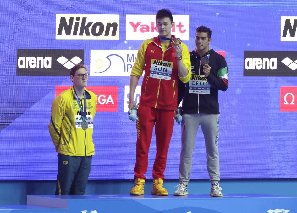 COURAGE: Australia's silver medallist Mack Horton stands away from the podium as Chinese mega star Sun Yang holds up his 400-metre gold medal alongside bronze medallist, Italy's Gabriele Detti, at the World Swimming Championships in Gwangju, South Korea. Picture: AP