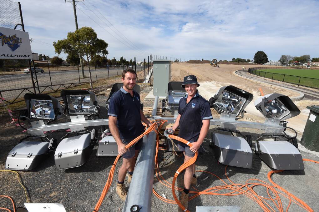 BEAMING: TJ Coutts electricians Jordan Liddie and Jack Owen work on wires for Eureka Stadium's powerful new light towers. Picture: Lachlan Bence