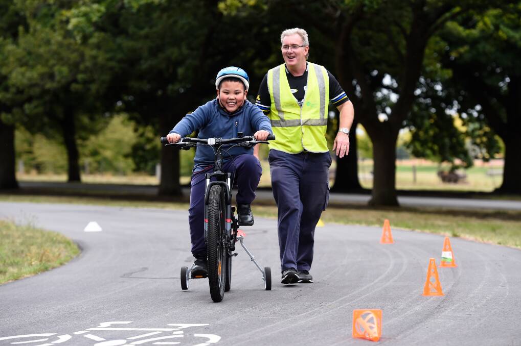 Ballarat-Sebastopol volunteer cycling coach Chris Liston leads a junior on course in the club's program for autistic children last year. Picture by Adam Trafford