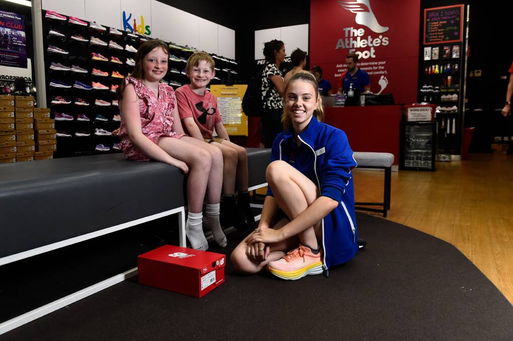 The Athlete's Foot's Lexi Oswin helps Imogen and Max Booker get fitted for school shoes on Tuesday. The Ballarat store donated more than 50 pairs of school shoes to help families in need via the Ballarat Christmas Appeal. Picture by Adam Trafford
