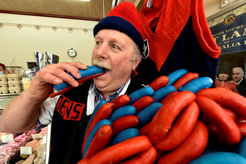 READY: Butcher John Harbour takes a bite into his Melbourne-themed hot dogs ahead of the AFL Grand Final. Picture: Jeremy Bannister