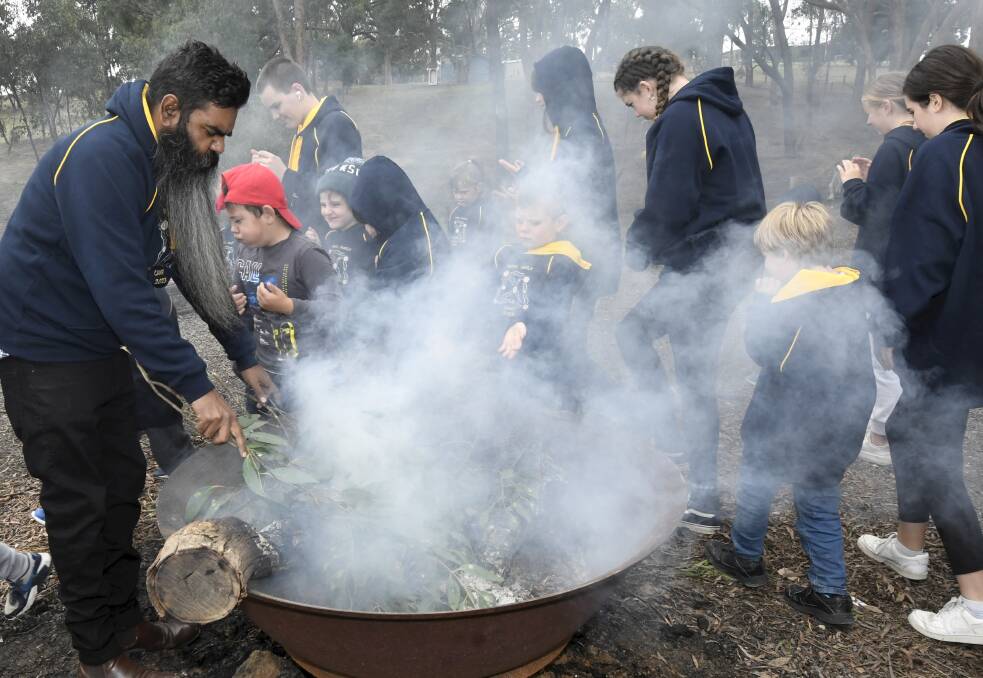 Ballarat and District Aboriginal Cooperative leader Shu Brown and children take part in a smoking ceremony at Log Cabin Camp in Creswick. Picture by Lachlan Bence