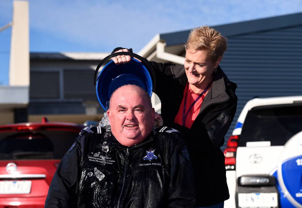 FROZEN: A shivering Leading Senior Constable Des Hudson takes bucket 11 from his wife Anne, pouring on behalf of a cousin in Bordertown. Picture: Adam Trafford