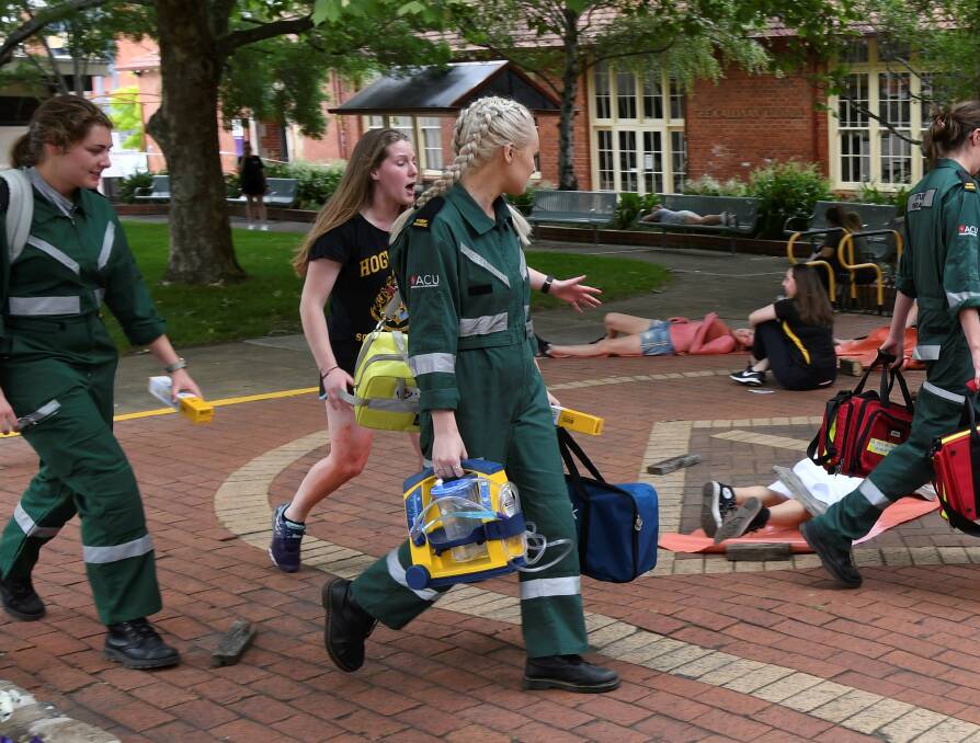SCENE: A distressed student appeals to ACU paramedic students for help in a post-bomb simulation in ACU's quadrangle as part of the training exercise, which also involved emergency services training. Picture: Lachlan Bence