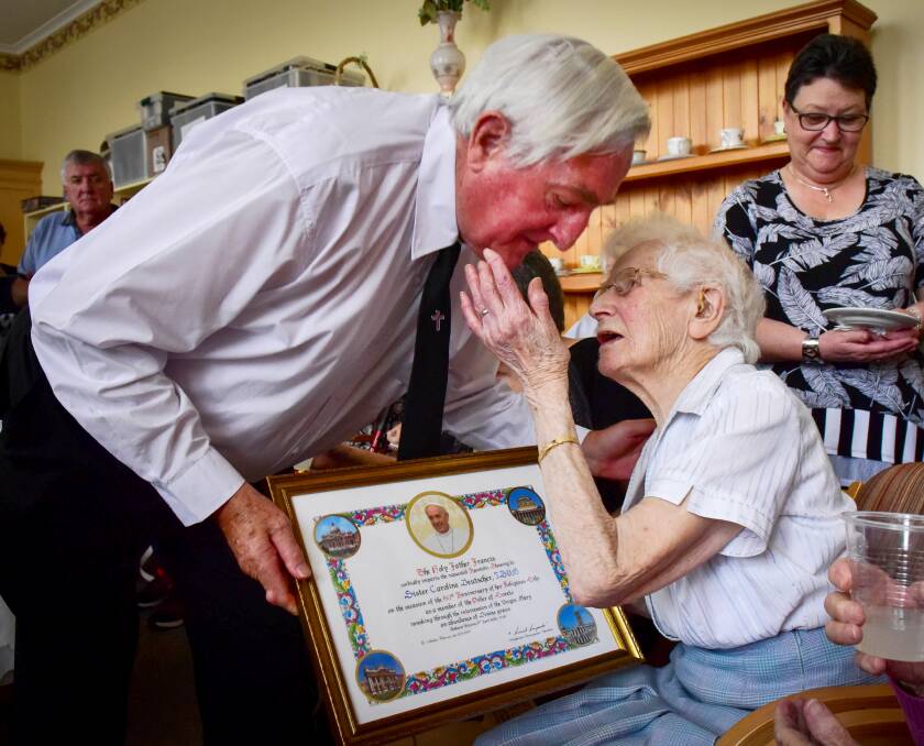 CELEBRATION: Father Peter Hudson presents an acknowledgement from the Pope to Sister Caroline Deutscher on her 100th birthday. Picture: Brendan McCarthy