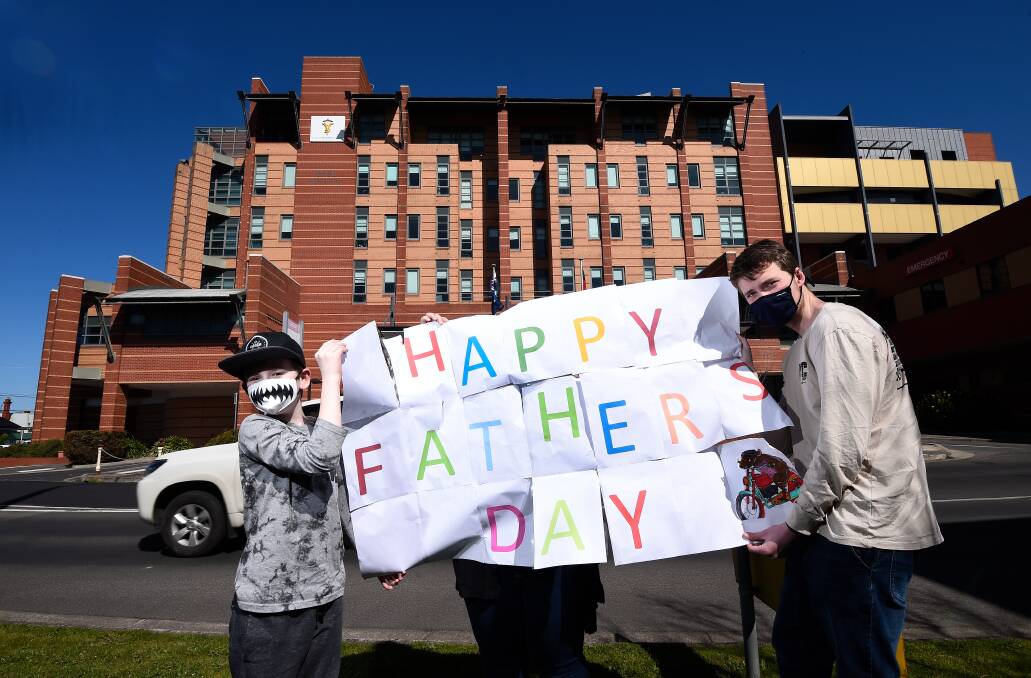 Saying hello: Brothers Xavier Prendergast and Jackson Grenfell hold a sign for their dad Kelvin, who has been in hospital for more than a week after surgery. Pictures: Adam Trafford