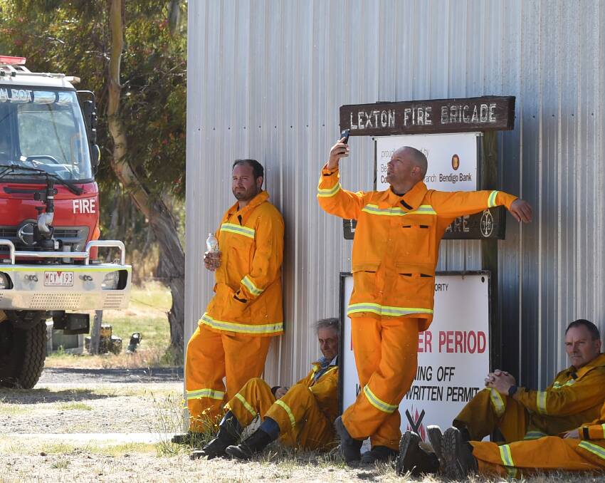 No signal: Firefighters take a breather at the Lexton fire station on Saturday morning, looking for mobile phone coverage. Picture: Kate Healy