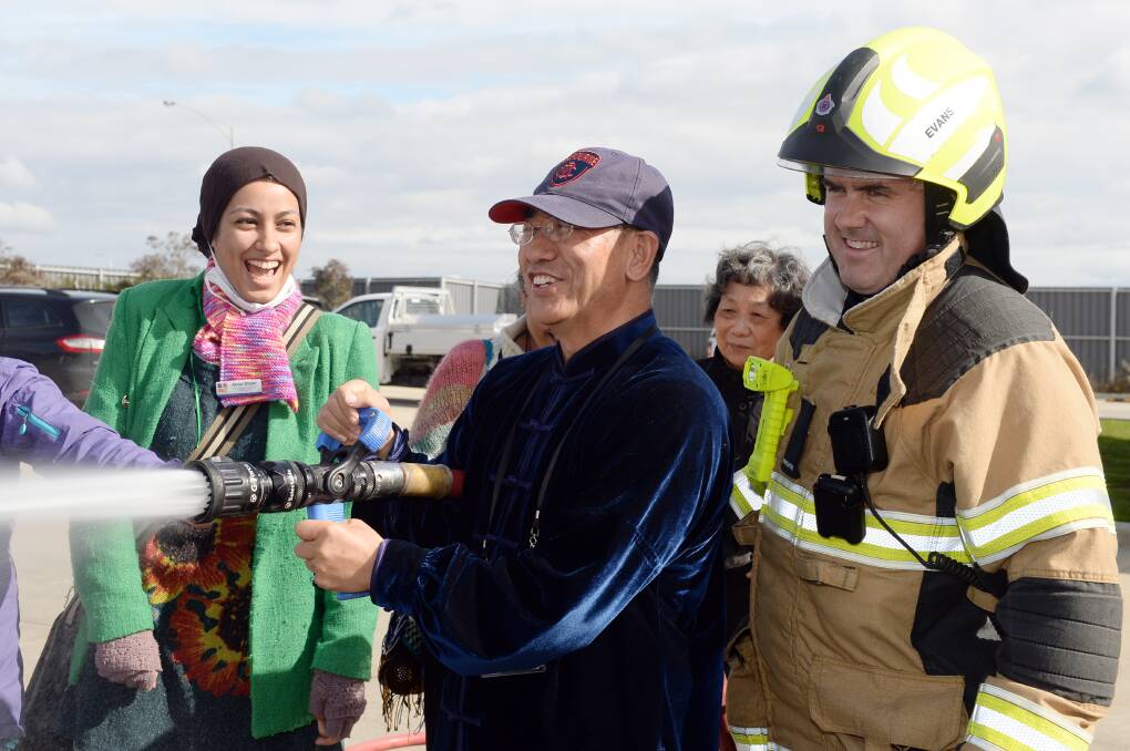 Firefighter Alan Evans showing Abrar Dham (BRMC, Settlement Support Coordinator) and Jack Yang (BRMC- Ballarat Regional Multicultural Council Inc. Volunteer) how to use the hose. Picture by Kate Healy
