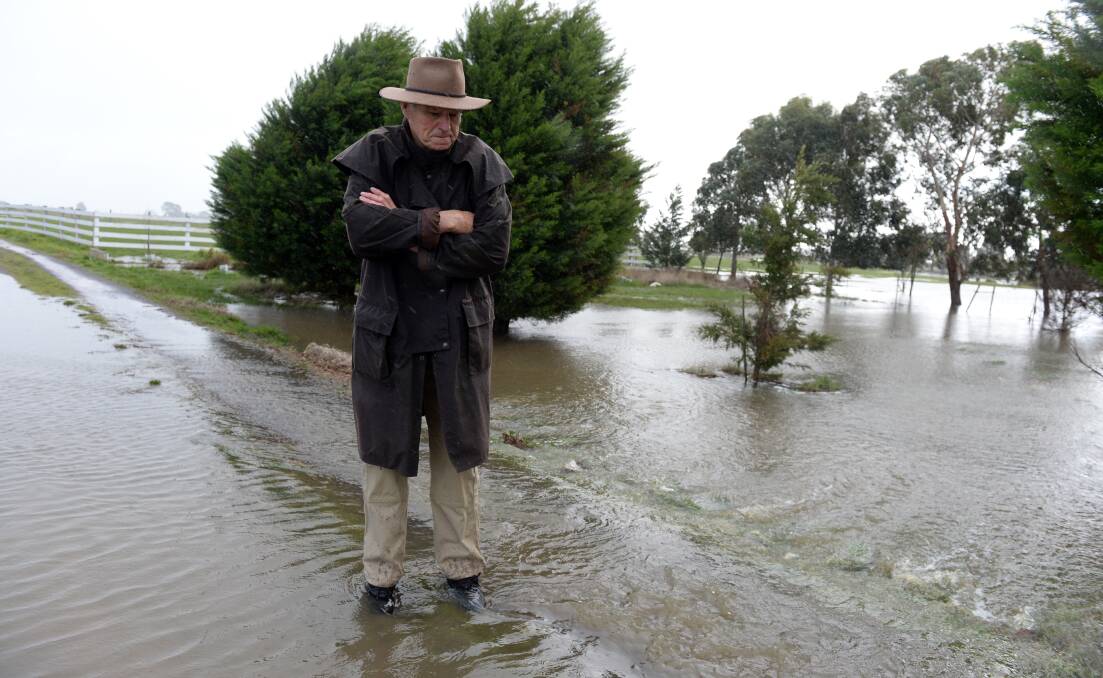 Deep water: David Dotzauer standing in the water on his property's driveway on Sunday. Pictures: Kate Healy