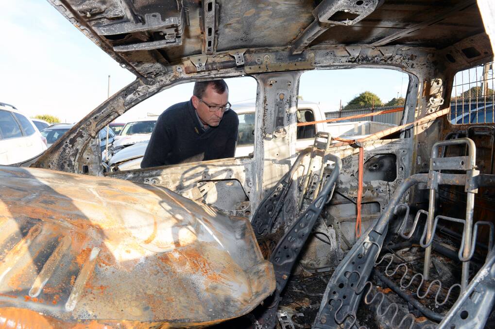 Frustration: Grant Parker with the burnt-out ute, recovered from bushland on Wednesday. Picture: Kate Healy