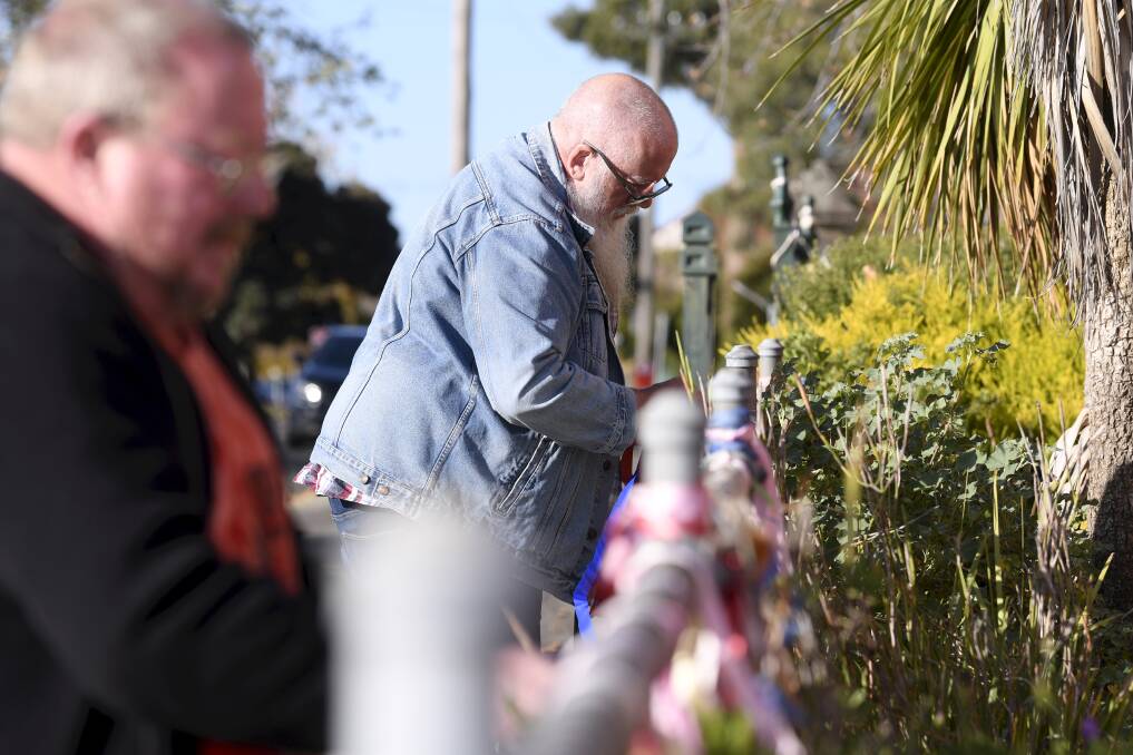 Support: Andrew Aiden ties a ribbon to the fence outside St Alipius on Victoria Street. Picture: Lachlan Bence