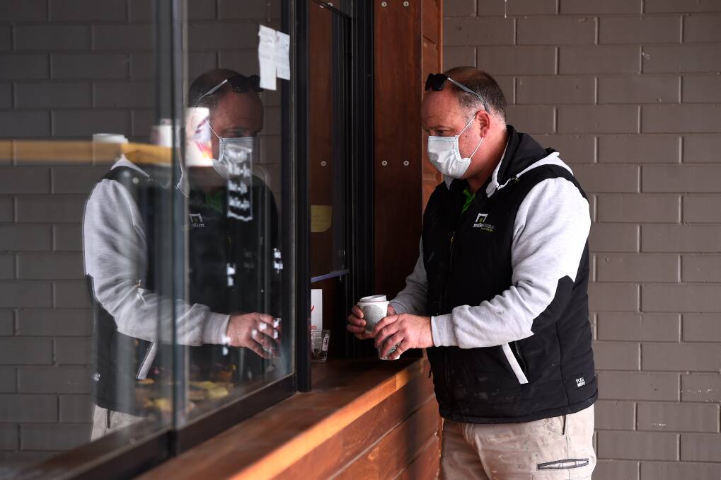 A man in a mask picks up takeaway coffee during the last lockdown. Picture: Adam Trafford