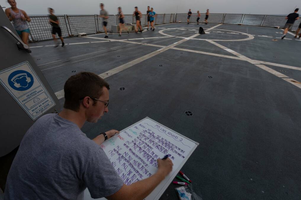 CHECK: Midshipman Gap Year Robert Fowler keeps track of the crew's 155-lap run on the flight deck in Run for a Cause. Picture: LSIS Shane Cameron, Australian Defence Force