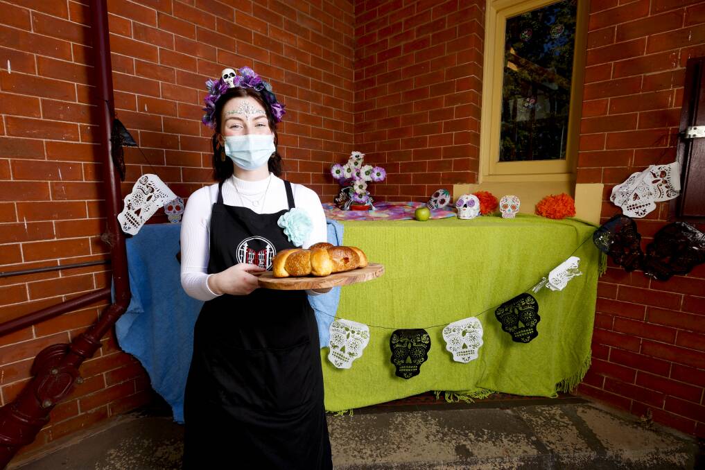 Georgia-Lily Young-Rosenhart with the pan de muerto at the Gatehouse Cafe's ofrenda altar. Picture: Luke Hemer
