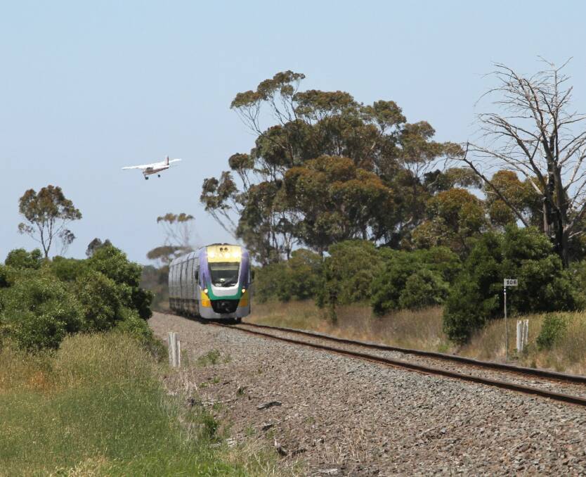 Buzzed: A plane flies over a V/Line train near Lethbridge. Picture: Marcus Wong