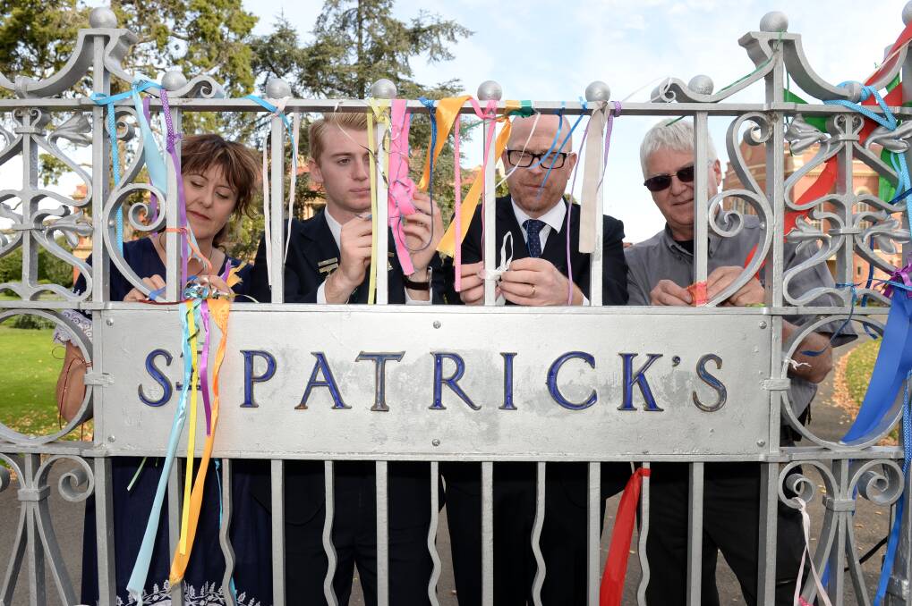 Maureen Hatcher, John Brodie, John Crowley and Phil Nagle carefully remove ribbons from the St Patrick's College fence. Picture: Kate Healy