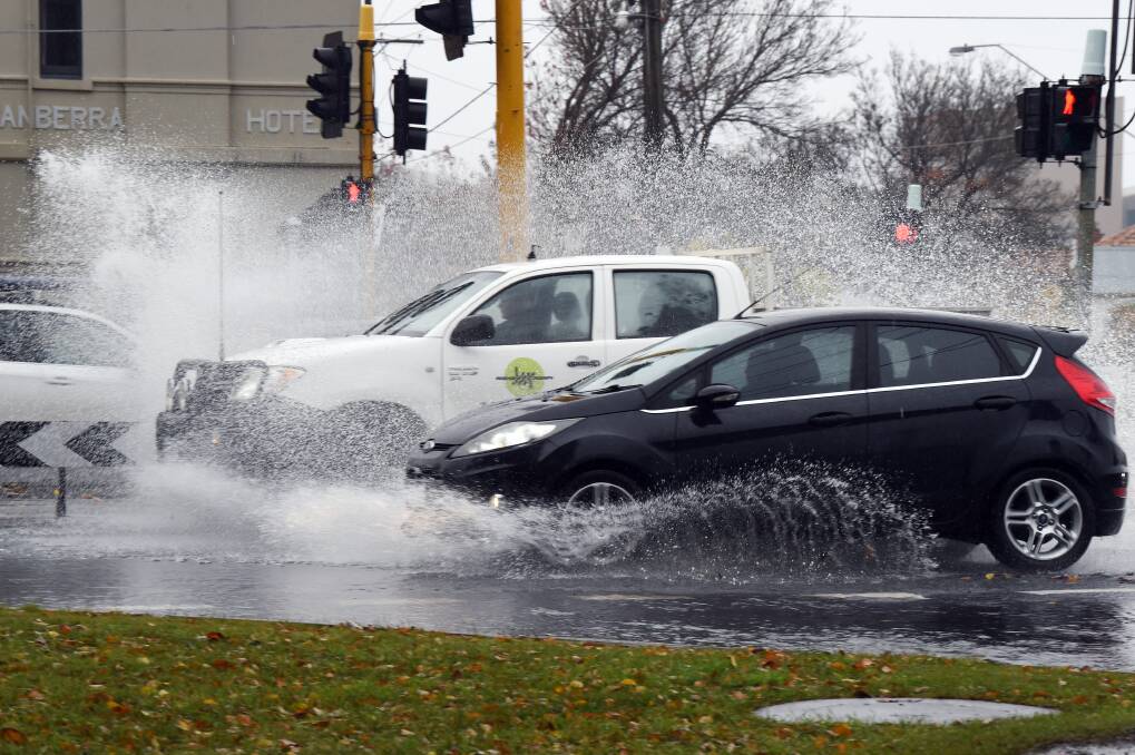 Cars go through water over Creswick Road near Macarthur Street. Picture: Kate Healy