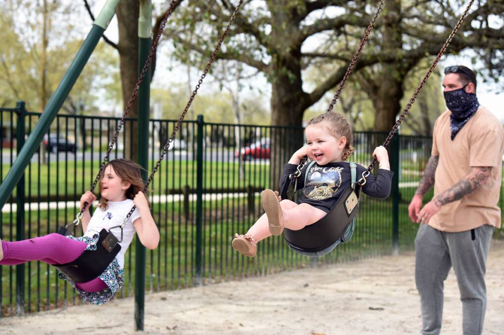 Out for a swing: Cousins Sophie Darby and Edie Beazley at Victoria Park, with Richard Beazley. Picture: Kate Healy