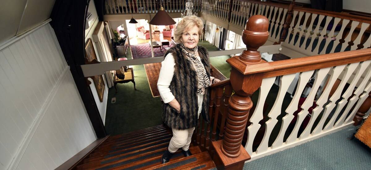 Golden age: Joyce Ryall, whose husband Keith was the mastermind behind Kryal Castle, standing on the impressive staircase in what used to be their residence, Ryallee Manor, which is currently on the market. Picture: Lachlan Bence