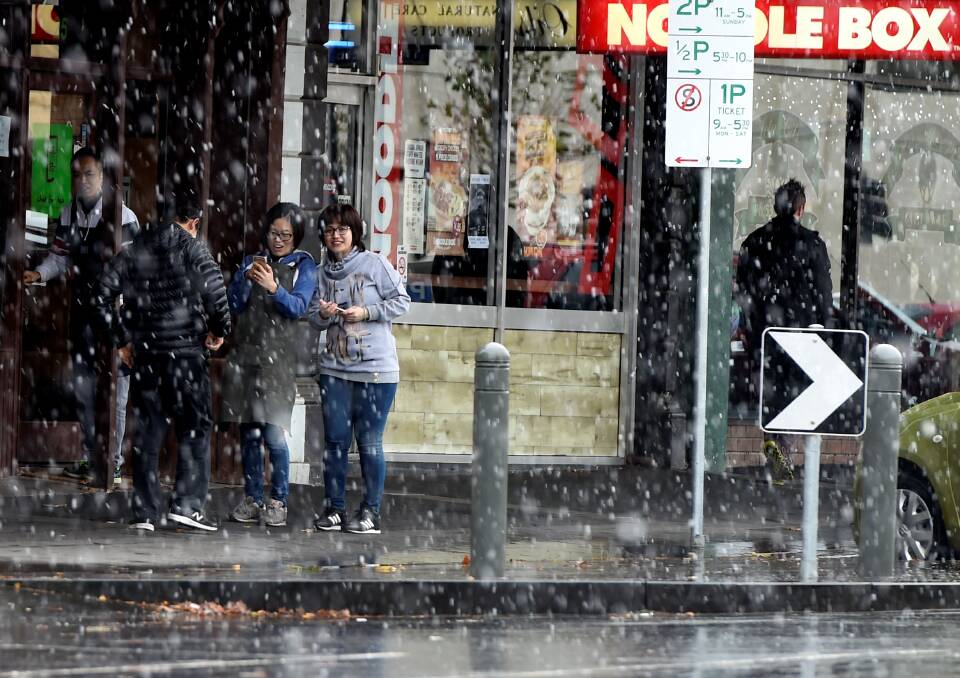 Taking shelter: The snow fell steadily in Ballarat's CBD from about 11am, with people taking shelter in Armstrong Street.