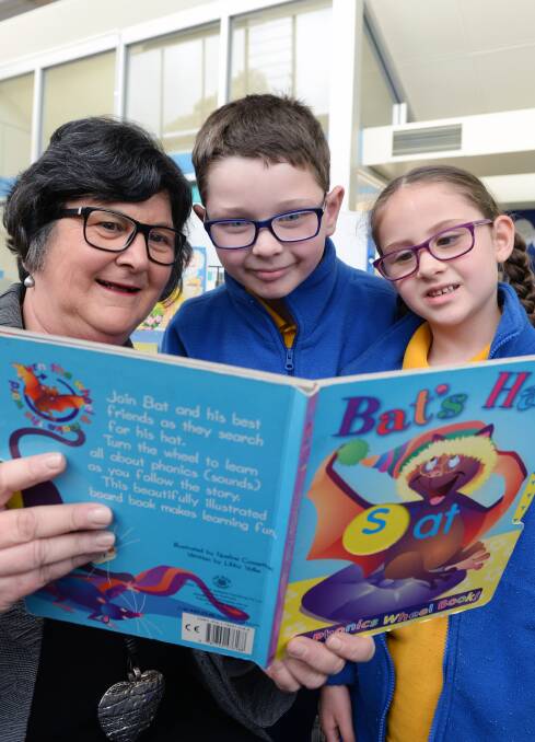 SEEING IT CLEARLY: Principal Michelle Wilson with Isaiah, grade 1 and Shakira, grade prep, use glasses to read a book. Picture: Kate Healy