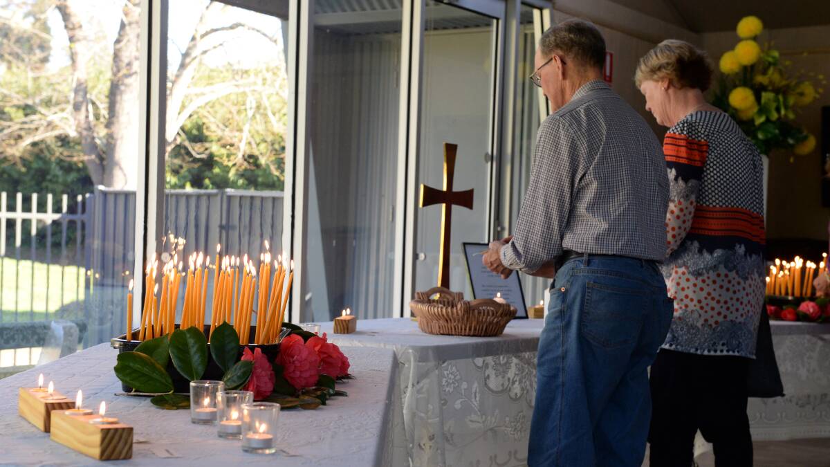 Mourners light a candle at the Buninyong Bowling Club in memory of Carmel Mitchell. Picture: Kate Healy