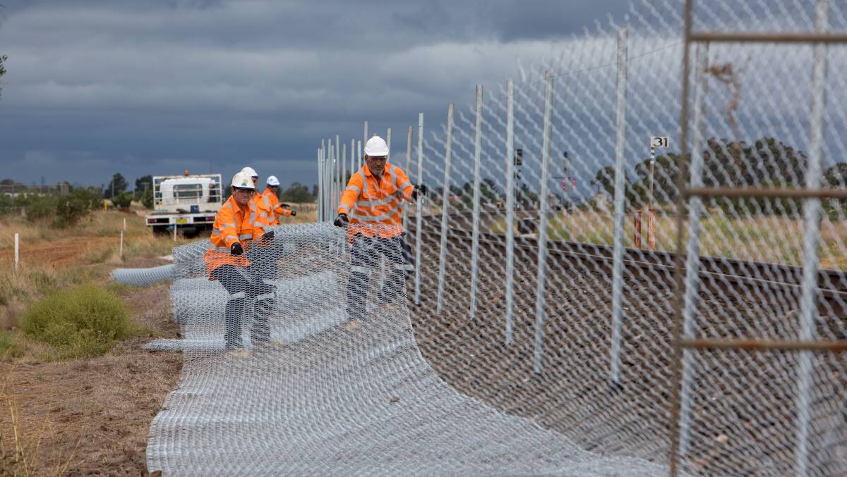 Keeping pace: Fencing being installed along the track between Melton and Caroline Springs, which allows work to continue while trains operate at full speed while works are underway. Picture: Regional Rail Revival 