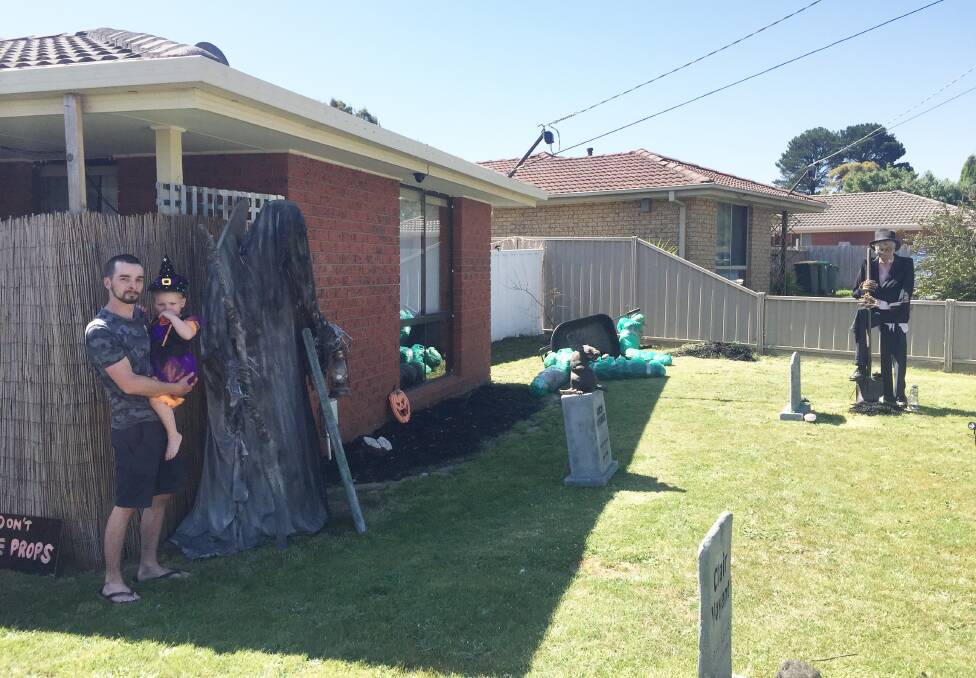 Garden of unearthly delights: Anthony Axford and his daughter Ruby standing in the yard of their Tarawa Drive home prior to Halloween. Picture: Caleb Cluff