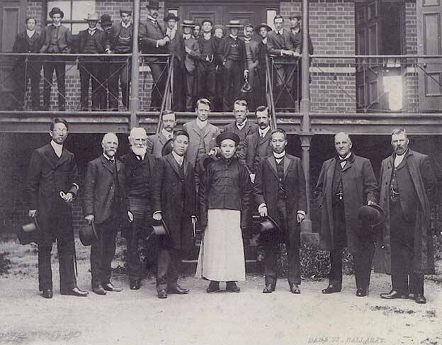 Another visit: Visit of the Chinese Commissioner to the Ballarat School of Mines, 23 November 1906. Twelve men pose for a photograph on the stairs of a building at the Ballarat School of Mines. Back row left to right: Archibald D. Gilchrist (Prof. of Engineering), Bertram Whittington (Mathematics, Physics), Thomas Hart (Prof. of Geology and Mining), John M. Sutherland (Electrical Engineering)
Front row left to right: Dr Wong Chock Son (Ballarat), Frederick Martell, Alfred Mica Smith, Ah Ket esq (Melbourne Barrister), His Excellency Hwang How Cheng (Chinese Commissioner), Wen Esq (Secretary), Alderman Grase (mayor of Brisbane), Grase Esq (Ballarat). Students of the Ballarat School of Mines stand in the background. Picture courtesy Federation University Historical Collection [Cat. No. 206].