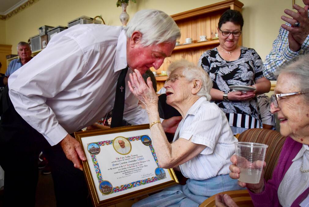 Father Peter Hudson presents an acknowledgement from the Pope to Sister Caroline Deutscher on her 100th birthday. Picture: Brendan McCarthy