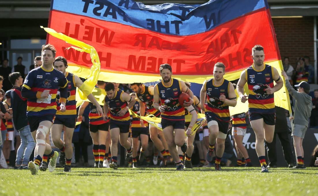 BLUE, RED AND GOLD: Beaufort senior players run through the banner at Mars Stadium before the start of the 2018 senior grand final.