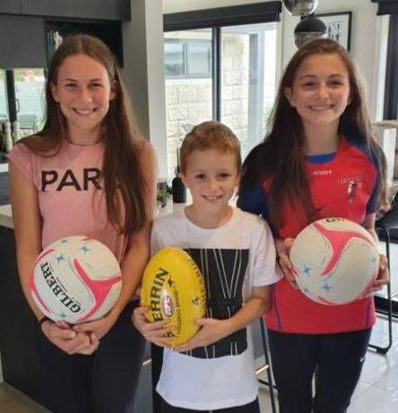 TIME TO PLAY: Paige, Chad and Heidi Torrance with the sporting equipment provided to them by the Hepburn Football Netball Club.