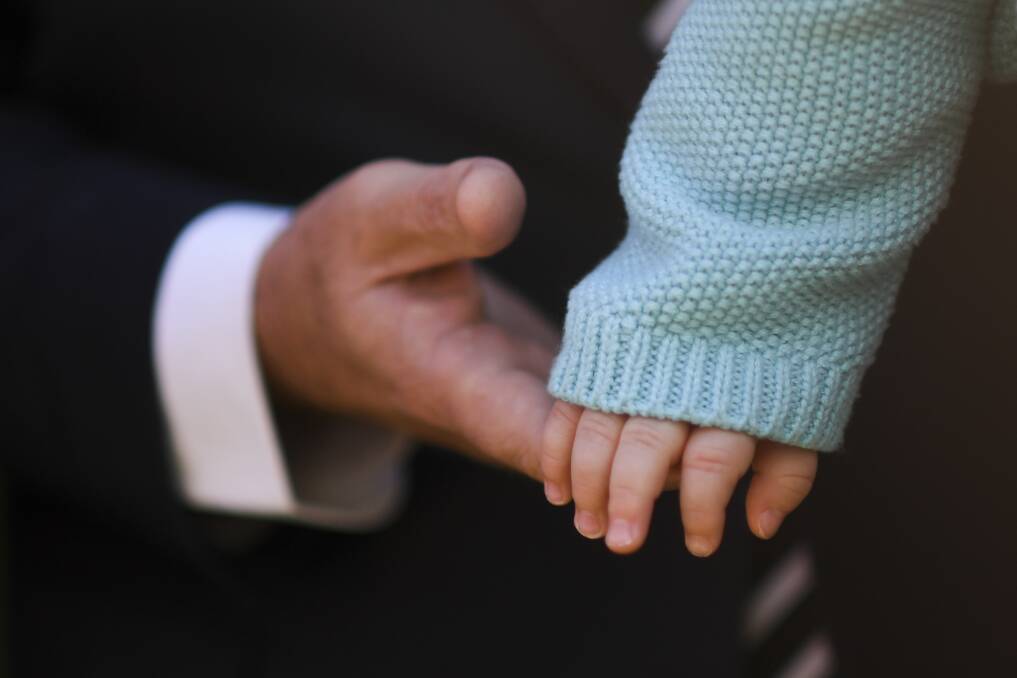 Australian Opposition Leader Bill Shorten holds the hand of seven-month-old Paul Phillips after an announcement on proposed superannuation changes for women and parents at Parliament House in Canberra. Picture: AAP
